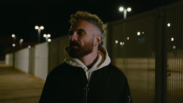 blu - jaboni fotografato all'aperto, di notte, indossa in giubbotto scuro e felpa grigia