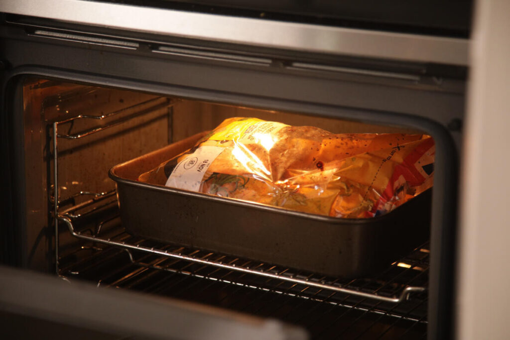 una teglia con del cibo confezionato in plastica dentro il microonde