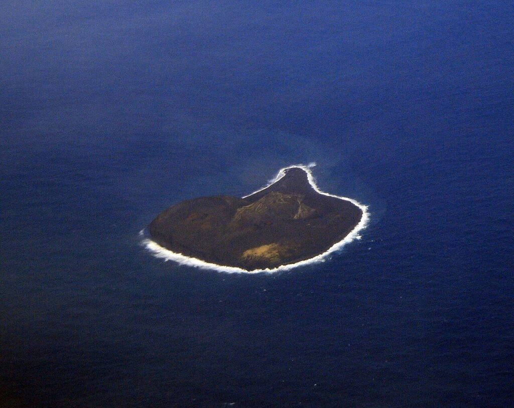 Isola di Surtsey fotografata dall'alto, in mezzo al mare blu.
