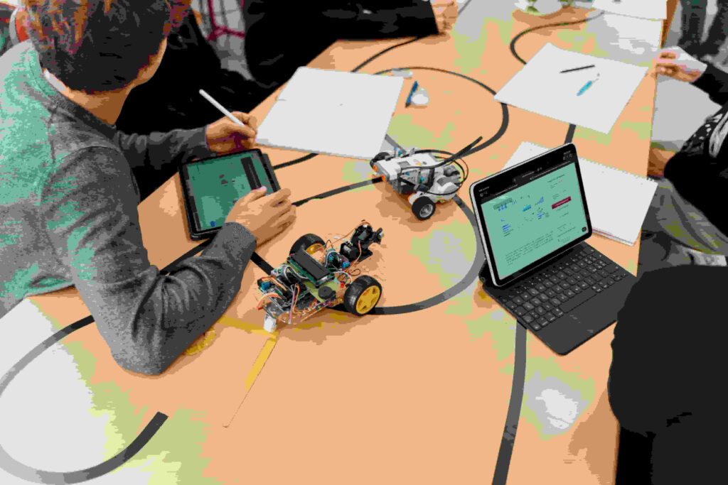 Liceo scientifico - su un tavolo ci sono dei dispositivi  e si intuiscono degli studenti che lavorano