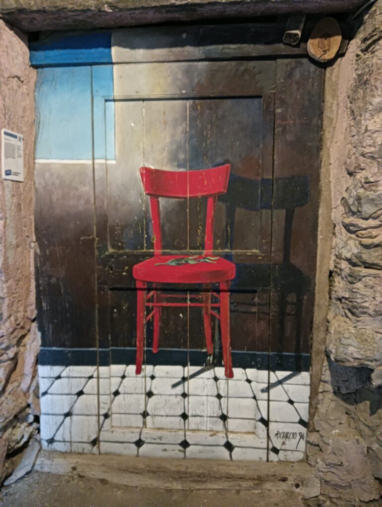 Valloria una porta dipinta con una sedia rossa e la sua ombra