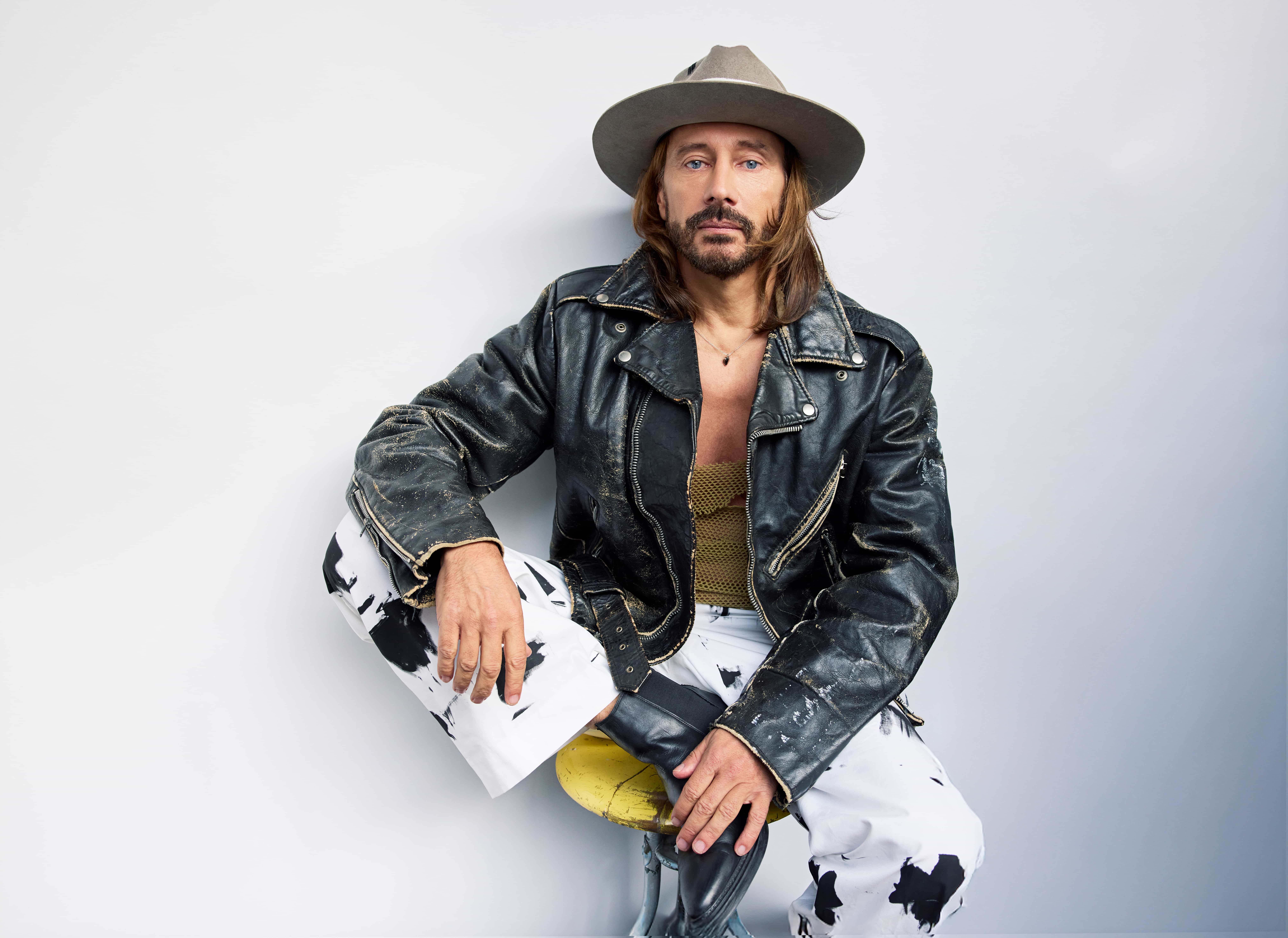 bobo sinclar in primo piano, indossa un cappello da cowboy, jeans bianchi e giubbotto di pelle scuro