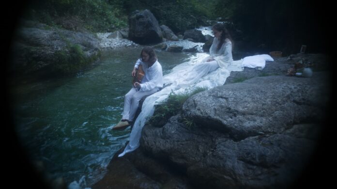 eyes be quiet - una stanza vuota - il duo fotografato su una roccia, nei pressi di un torrente, vestiti entrambi di bianco