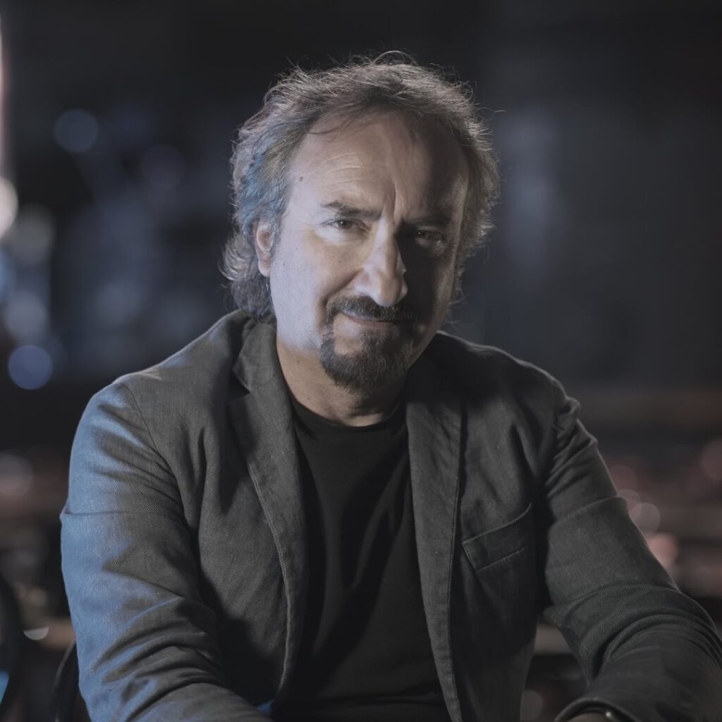 LAZIOSound PAolo Vita seduto a mezzo busto indossa giacca e t shiurt scura, ha capelli lunghi sulle orecchie e porta baffi e pizzetto