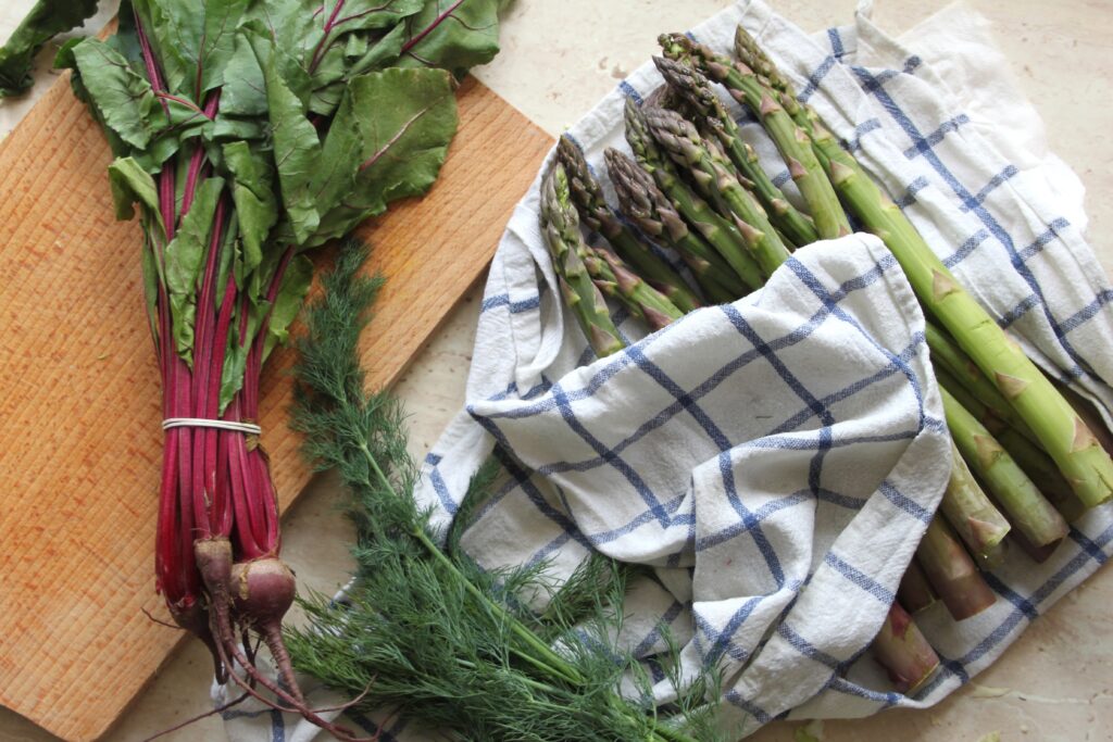 cosa cucinare in primavera - nella foto degli asparagi avvolti inun cacnnavaccio e vicino dell'anneto verde e dei cipollotti ross