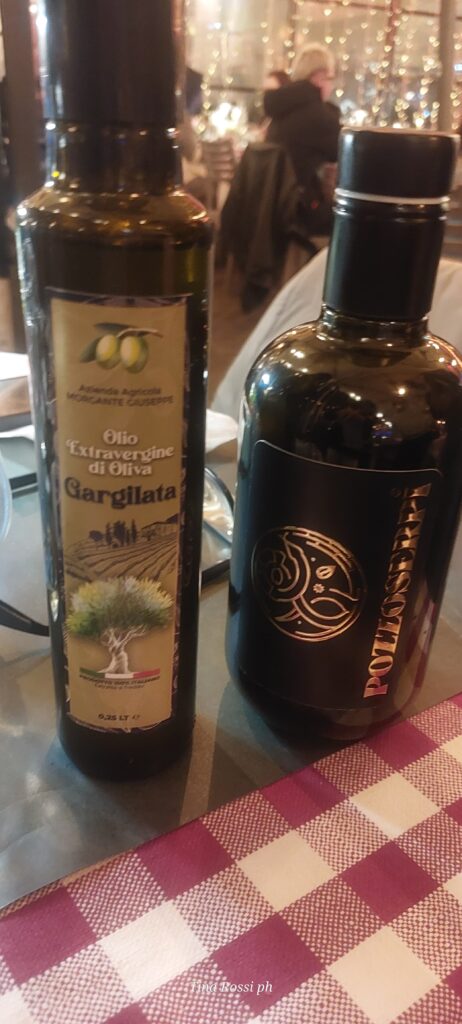 ristorante Vrigilio - duebottiglie d'olio appoggiate su un tavolo coperto da una tovaglia a quadretti rossi e bianchi