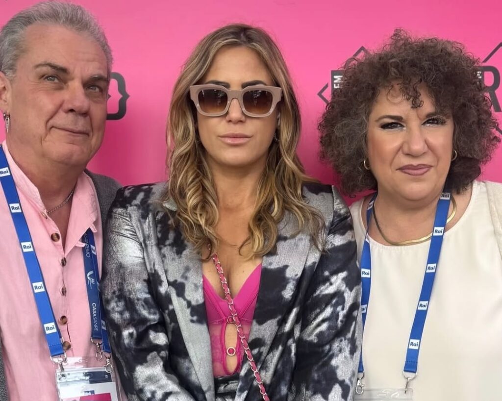 Da sinistra a destra Lele Boccardo, capelli brizzolati, camicia rosa, al centro Michelle capelli biondi lunghi indossa occhiali da sole e giacca fiorita, A destra Tina Rossi capelli ricci neri indossa una camicia chiara