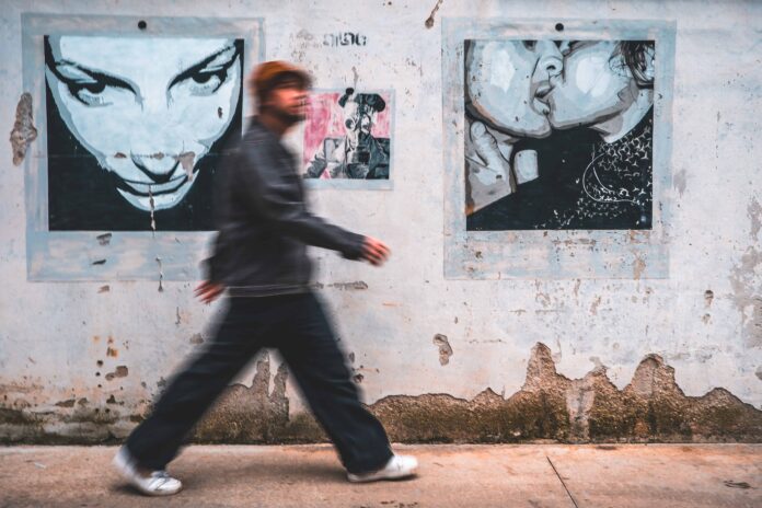 Sbalzi il singolo d'esordio di Pricci - Zetatielle Magazine sbalzi - il cantautore pricci (in una mmagine sfocata) cammina davanti a un muro dipinto con dei murales