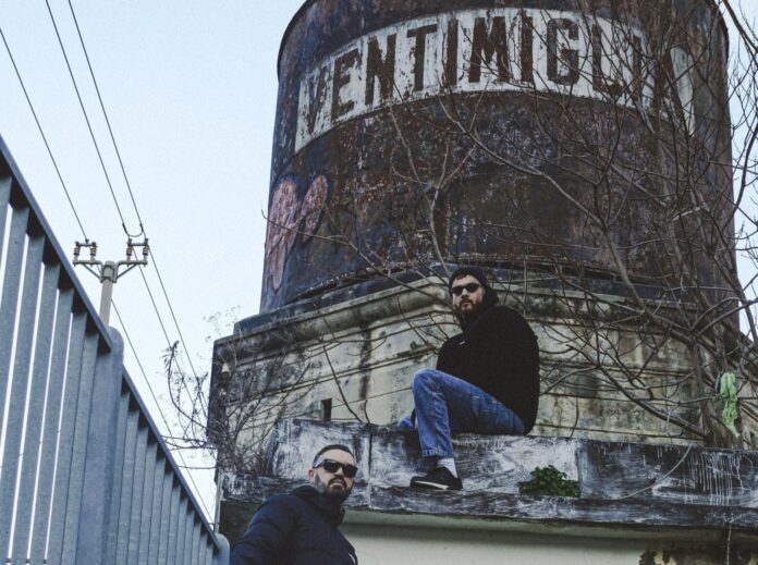 naesh - vita lenta - il rapper in primo piano davanti a un cartello indicante la città di ventimiglia