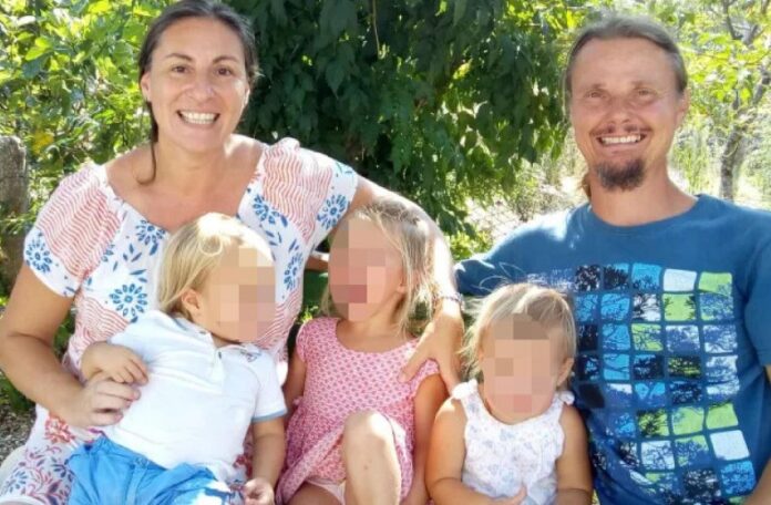 la famiglia nel bosco con la madre a sinistra sorridente con capelli neri raccolti, a destra il papà biondo con baba e baffi, al centro i tre bambini con il viso oscurato epr la privacy