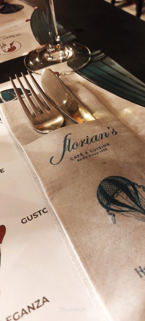 delle posate spuntano da un tovagliolo piegato con la scritta "Florian's café