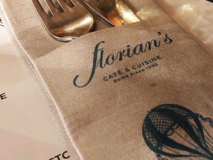 delle posate spuntano da un tovagliolo piegato con la scritta 