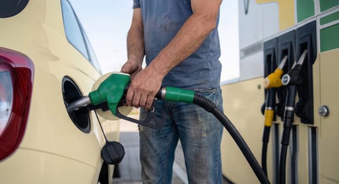 Benzina raziona e carburante: nella foto un uomo sta tenendo in mano una pistola di colre verde del distributore di benzina e sta facendo rifornimento all'auto gialla