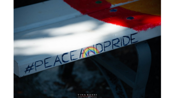 Carta Arcobaleno LGBTQIA+ - nella foto una panchina bianca e con una striscia rossa e in primo piano la scritta #peaceandpride