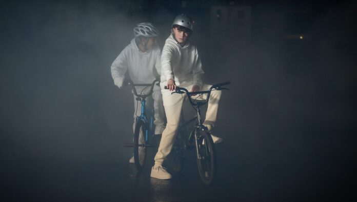 Film Club la miniserie BBC in esclusiva su RaiPlay - zetatielle Magazine - 4860 Film Club 241128 Day15 1594 (1) film club - raiplay - nella foto due persone in bicicletta, al buio, che indossano una tuta bianca da astronauta