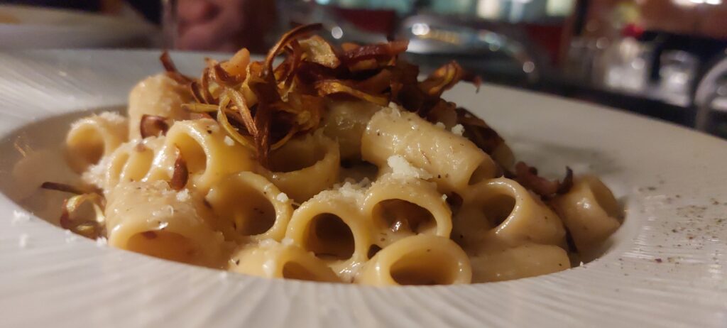 un piatto di maccheroni con sopra delle briciole di carciofi