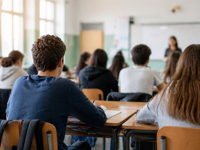 Carta Valore bonus cultura - in una aula di scuola si vedono degli studenti seduti ai banchi di schiena - immagine generata con IA