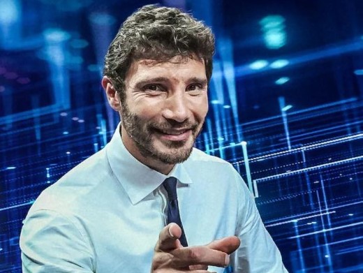 Stasera tutto è possibile - Stefano De Martino in primo piano indossa camicia bianca cravatta nera punta il dito verso l obiettivo e sorride