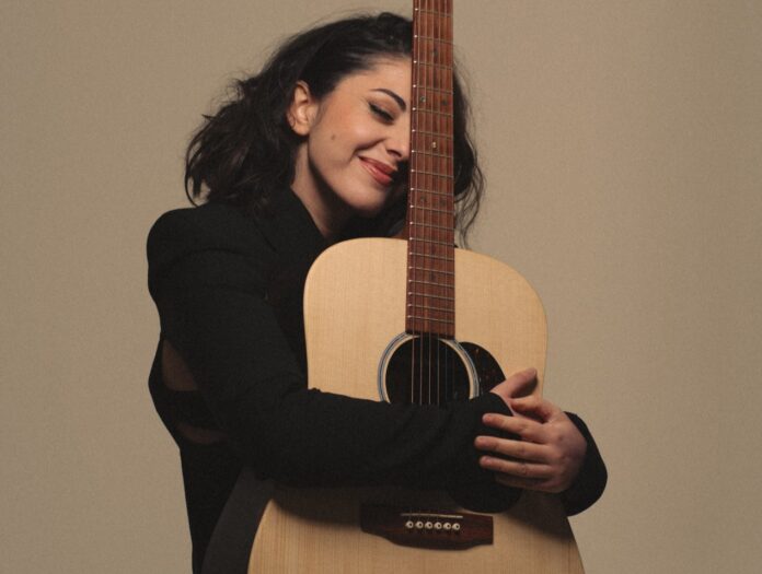 amanda vitale - terra mia - la cantante vestita di scuro mentre abbraccia una chitarra