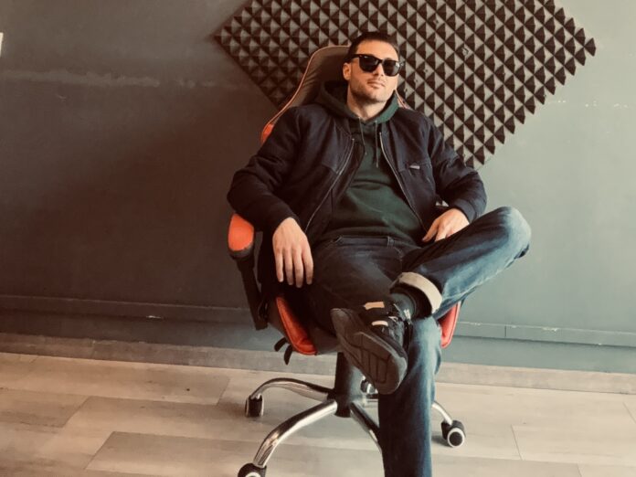 Andrea Manocchio, e il cielo non ha più confini nuovo singolo e videoclip - Zetatielle Magazine andrea manocchio in primo piano, seduto su una sedia girevole, con le gambe accavallate