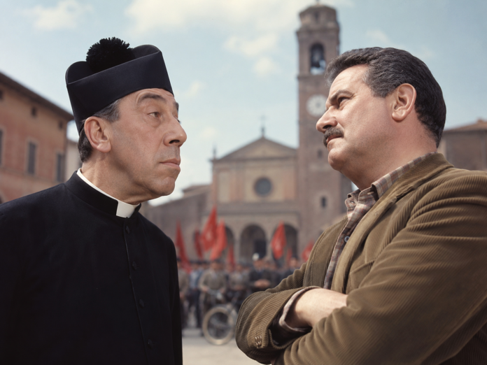 Don Camillo e Peppone, perché la loro saga continua a parlare all'Italia di oggi - Zetatielle Magazine - ChatGPT Image 11 giu 2026, 11_44_44 don camillo e peppone in primo piano, sullo sfondo il campanile di una chiesa