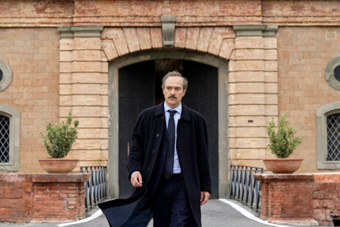 “Libri Liberi” fa tappa a Bollate (MI) - claudio santamaria - zetatielle magazine - Libri liberi Claudio Santamaria .- nella foto l'attore indossa giacca e cravatta e impermeabile nero, porta i baffi e sta camminando con alle spalle un edificio