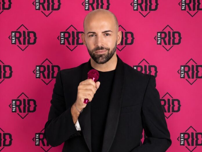 Angelo Rifino conquista il microfono d oro - rid968fm - zetatielle magazine Angelo Rifino con giacca e maglietta nera, tiene in mano un microfono rosa, ha barba e baffi , sorride