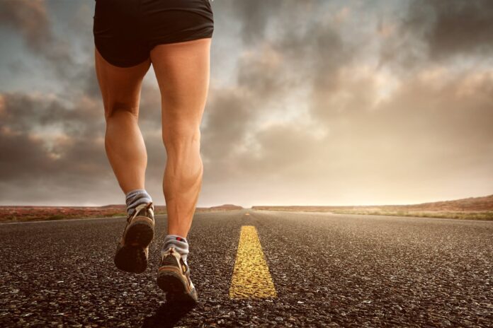 La corsa di una vita, il nuovo libro di Piergiorgio Galli - ZETATIELLE MAGAZINE - kinkate-jogging-2343558 in primo piano le gambe di una persona che corre su una strada deserta con la striscia di mezzeria gialla e all orizzonte sole e nuvole