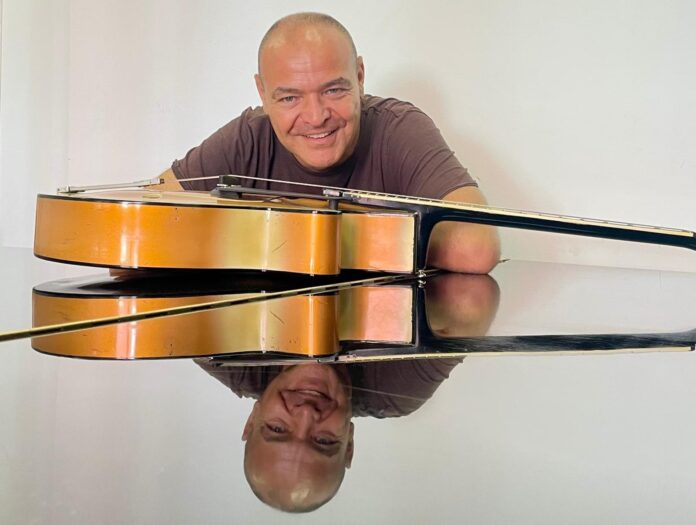 MICKI illumina l'estate con Come una lucciola il nuovo singolo tra soul e poesia - Zetatielle Magazine micki - come una lucciola - il cantautore romano sorridente ha una chiatarra aoopggiata davanti al viso