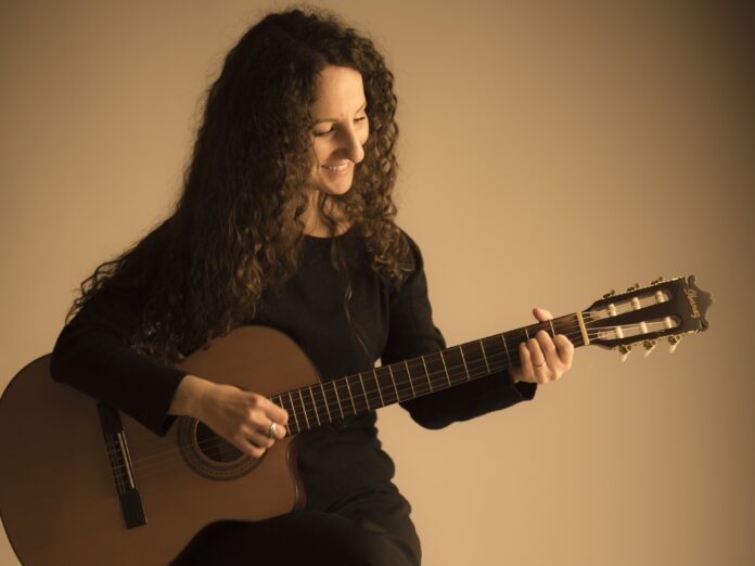 Marta Maggio, Se fossi è un liberatorio atto di pace - Zetatielle Magazine marta maggio, seduta su uno sgabello, intenta a suonare una chitarra acustica